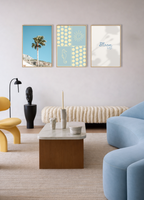 Gallery wall mockup van Bloom Archives met de Seaside Stories poster in blauw, gecombineerd met de posters Bloom Up en Analog Palm in een moderne woonkamer met zachte blauwe en neutrale tinten.