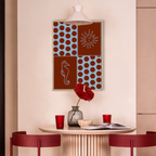 Seaside Stories fine art poster van Bloom Archives in een stijlvolle eethoek met warme rode accenten, grafisch kustdesign met zon, zeepaard en speels patroon als moderne wanddecoratie.